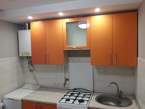 uma pequena cozinha com armários laranja e um lavatório em Apartment On Rabochaya 81 em Dnipro