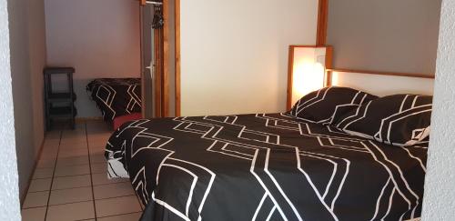 a bedroom with a bed with a black and white comforter at Hôtel Eco Logis Espace Bellevue in Séméac