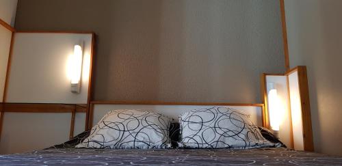 a bedroom with two pillows on a bed with two lights at Hôtel Eco Logis Espace Bellevue in Séméac
