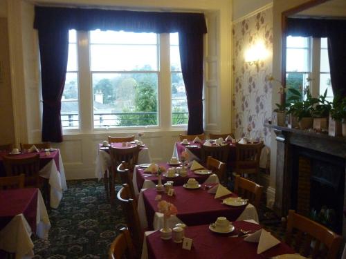 a dining room with tables and chairs and a fireplace at Ashwood Grange in Torquay