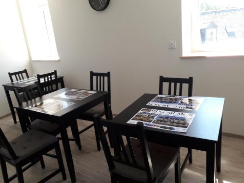 CHAMBRES D'HOTES PORTSALL في Ploudalmézeau: غرفة طعام مع طاولتين وكراسي عليها صحف