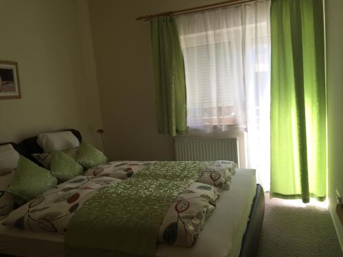 ヘーヴィーズにあるHolident Hévíz Apartmanのベッドルーム1室(緑のカーテンと窓付きのベッド1台付)