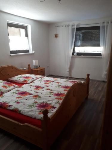 a bedroom with a bed with a floral comforter and two windows at Am Wiesengrund - mit 2 Schlafzimmern in Ribnitz-Damgarten