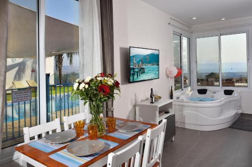 a bathroom with a tub and a table with flowers on it at shmulik's resort couples or families only in Had Nes