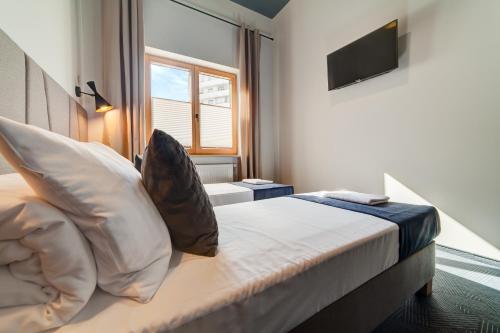 a bedroom with a bed with pillows and a television at GoldApartRooms in Białystok