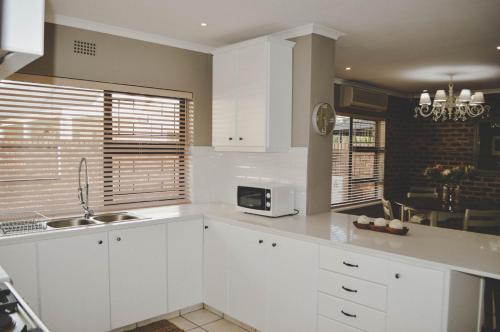 Una cocina blanca con fregadero y microondas. en Villa Bon Chretien, en Stellenbosch