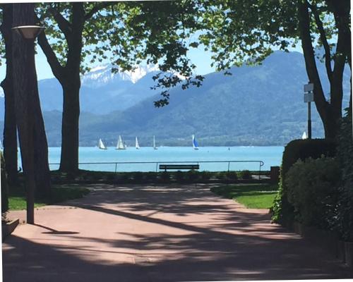 a park with a bench and sailboats in the water at The One Suite Annecy in Annecy