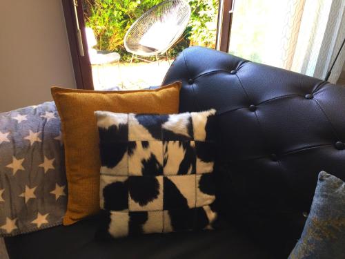 a black leather couch with pillows and a fan at The One Suite Annecy in Annecy