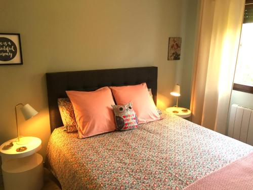 un letto con cuscini rosa e un orsacchiotto. di The One Suite Annecy ad Annecy