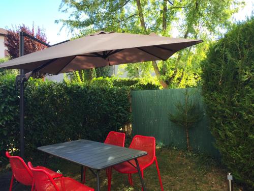 a table and four red chairs under an umbrella at The One Suite Annecy in Annecy