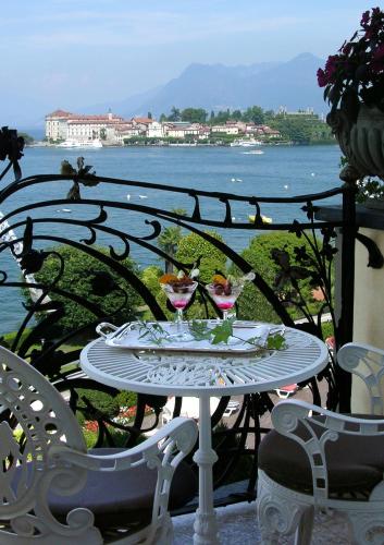 a table with drinks on a balcony with a view of the water at Hotel Villa e Palazzo Aminta in Stresa