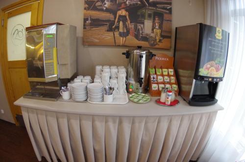 a counter with cups and plates and a coffee maker at Hotel Vadászkürt Superior in Székesfehérvár