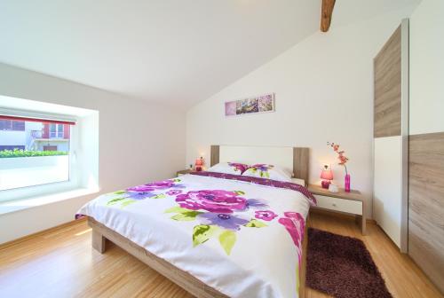a white bedroom with a bed with flowers on it at Apartments Muciceva Ravan in Jurdani