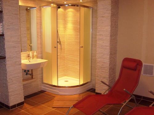 a bathroom with a shower and a sink and a red chair at Willa Lawenda in Duszniki Zdrój