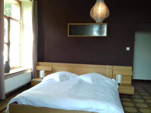 a bedroom with a white bed with a brown wall at Thirifays, résidence de vacances in Chiny