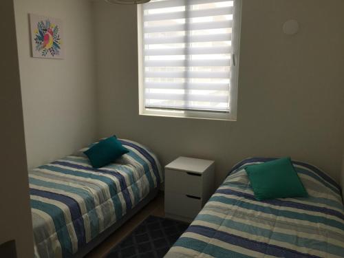 拉塞雷納的住宿－Departamento La Serena 6 Personas，一间卧室设有两张单人床和一个窗户。