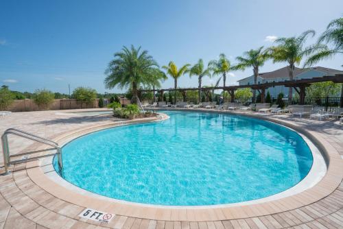 a pool at a resort with chairs and palm trees at Dream Vacation Home! in Kissimmee