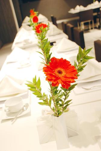 a vase filled with red flowers on a table at Met Hotel in Izmir
