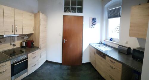 cocina con armarios de madera, fregadero y ventana en Ferienwohnungen zur Post - 102, en Weidenberg