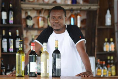 a man standing behind a counter with wine bottles at Villa Dahl Beach Resort in Dar es Salaam