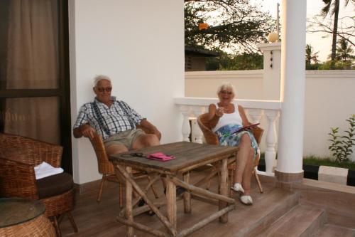 an older man and woman sitting at a table on a porch at Villa Dahl Beach Resort in Dar es Salaam