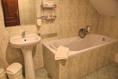 a bathroom with a sink and a tub and a toilet at BIRDIE Pension & Wellness in Pardubice