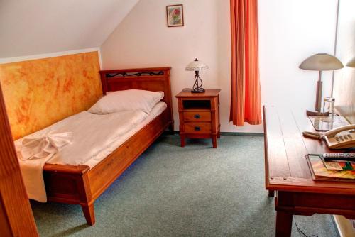 a bedroom with a bed and a table and a desk at BIRDIE Pension & Wellness in Pardubice