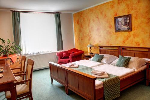 a bedroom with a bed and a table and a chair at BIRDIE Pension & Wellness in Pardubice