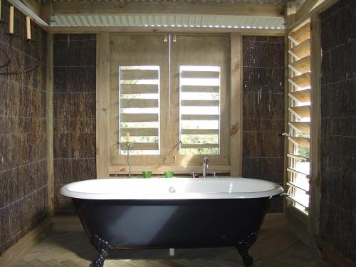 uma banheira na casa de banho com uma janela em Island Breeze em Oneroa