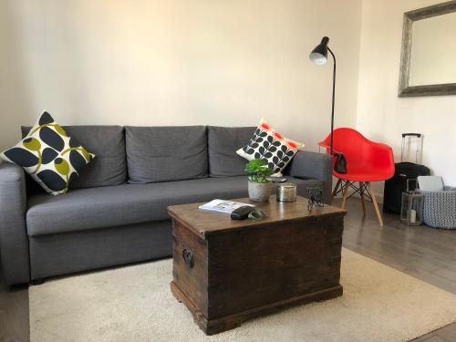 a living room with a gray couch and a red chair at La casetta d'Àneu in Oxford