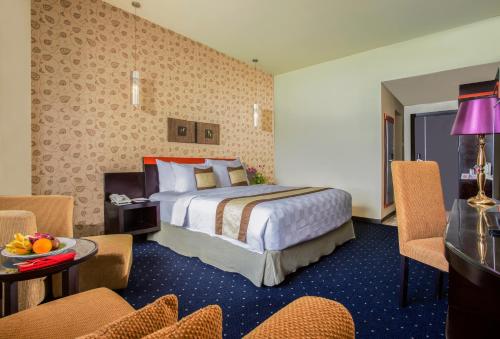 a hotel room with a bed and a table and chairs at Swiss-Belhotel Silae Palu in Palu
