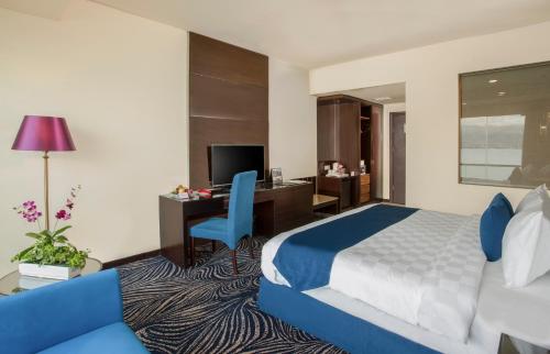 a hotel room with a bed and a desk at Swiss-Belhotel Silae Palu in Palu