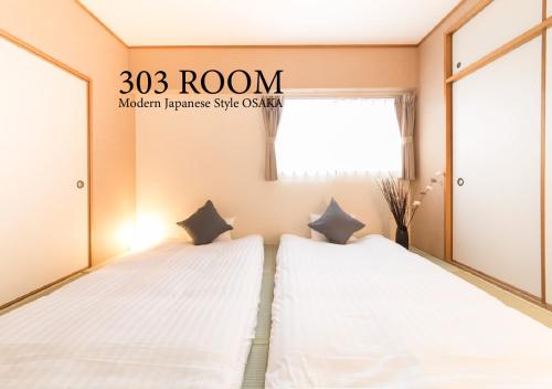 two twin beds in a room with a window at Jpride Uemachidai Condo in Osaka