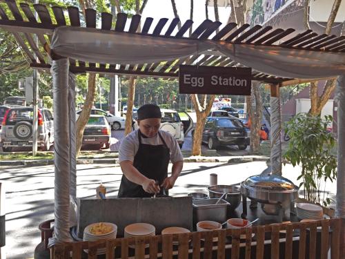 Um homem está a preparar comida numa barraca de comida. em Dreamtel Kota Kinabalu em Kota Kinabalu