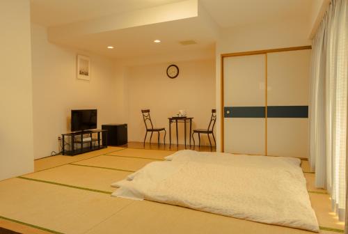 a bedroom with a bed and a table with chairs at Tsushima Dae-A Hotel in Tsushima