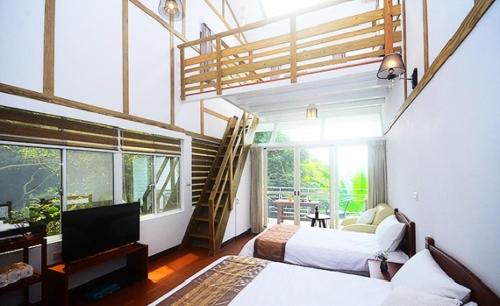 a bedroom with two beds and a television and a staircase at Pear Story House in Dongshi