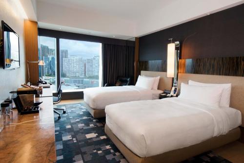 a hotel room with two beds and a large window at Hotel ICON in Hong Kong