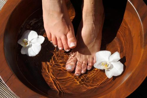 a person standing in a bowl of water with white flowers at Hotel Dolomitenblick in Collalbo