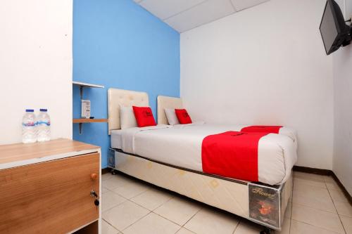 RedDoorz Near Kota Lama Semarang في سيمارانغ: غرفة نوم عليها سرير ومخدات حمراء