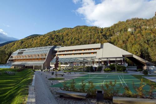 a building with a tennis court in front of it at Hotel Špik in Kranjska Gora