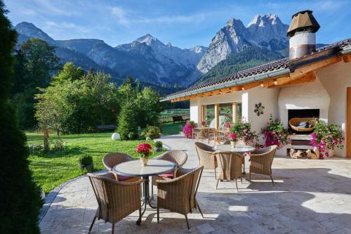 a patio with tables and chairs with mountains in the background at Boutique Hotel Längenfelder Hof in Grainau