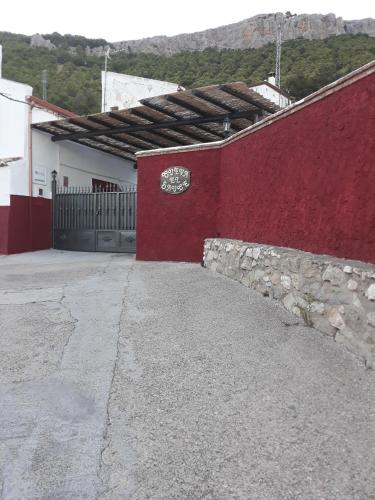 a red wall with a gate and a driveway at Casa Rural Cueva El Sauce in Pegalajar