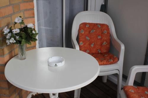 un tavolo bianco e una sedia con un vaso di fiori di Residenz Ostseestrand Nr_ 11 a Scharbeutz