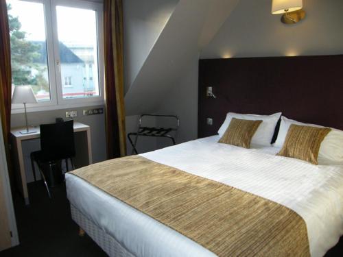 a bedroom with a bed and a desk and a window at CIT'HOTEL Saint-Pierre in Vire