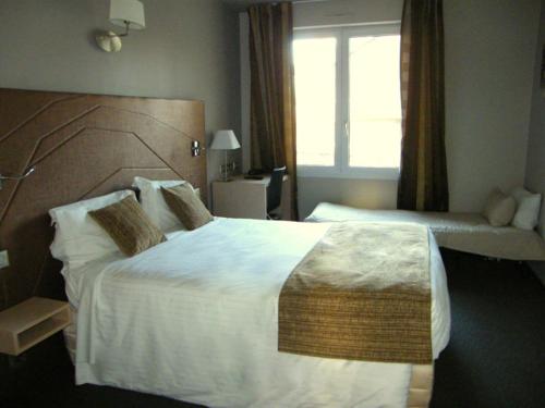 a hotel room with a large bed and a window at CIT'HOTEL Saint-Pierre in Vire