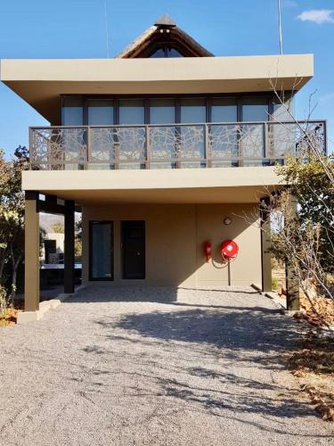 a house with a balcony on top of it at Kuwisa Lodge in Bela-Bela