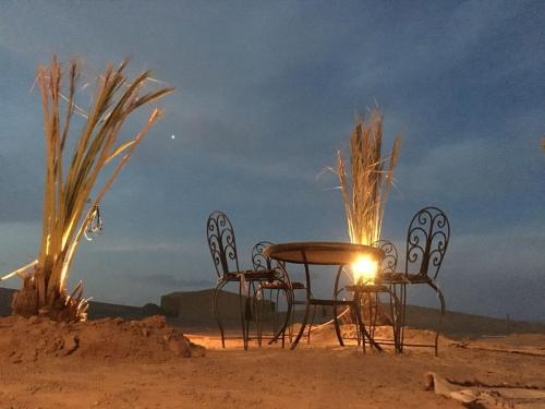 a table and chairs in the desert at night at Bivouac Le Ciel Bleu in Erfoud
