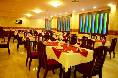 Kodungallūr的住宿－Seashore Residency，餐厅设有白色的桌椅和色彩缤纷的窗户。