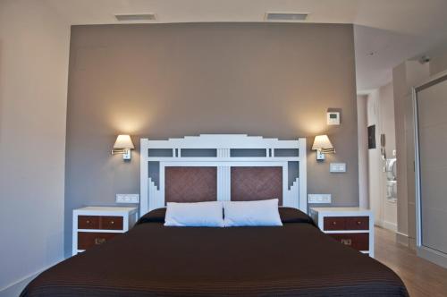 una camera con un grande letto e due comodini di Apartamentos Rondacentro a Ronda