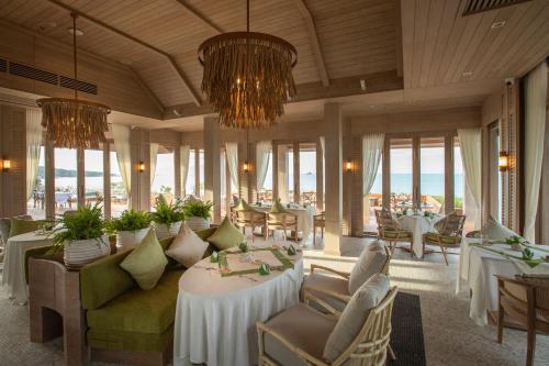a restaurant with tables and chairs and a chandelier at Cape Fahn Hotel - Private Islands Samui in Choeng Mon Beach